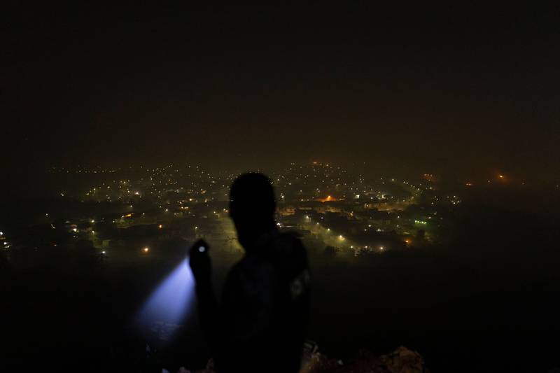 A private security guard scouts the surroundings using his torchlight from a hill facing Mount Moriah suburb in North of Durban. Countrywide blackouts of up to 12 hours a day are rolling across South Africa. AFP