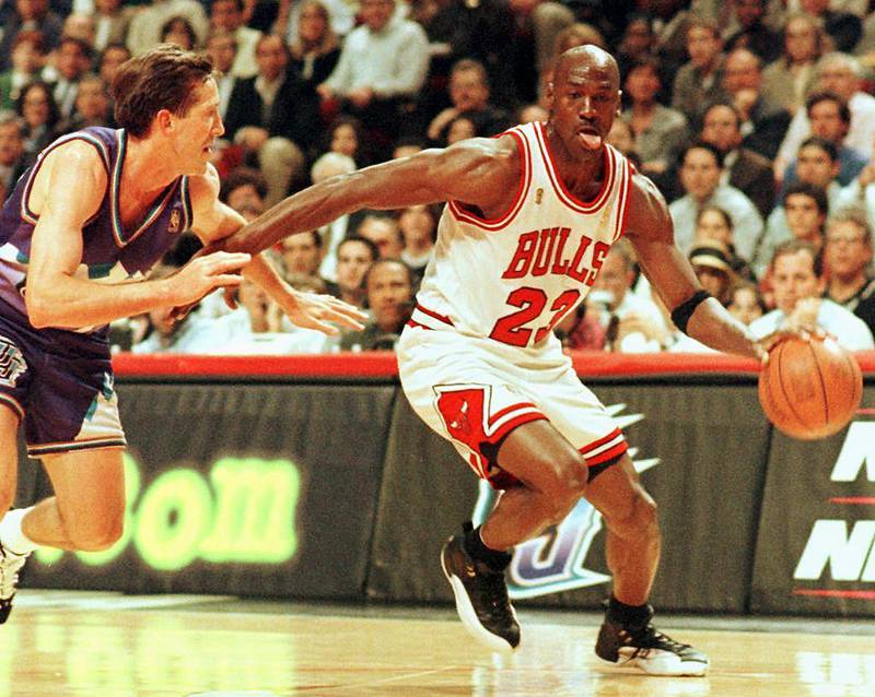 (FILES) In this file photo taken on June 4, 1997 Chicago Bulls player Michael Jordan sticks out his tongue as he goes past Jeff Hornacek of the Utah Jazz during game two of the NBA Finals at the United Center in Chicago, IL. The immense global success of the documentary "The Last Dance" amid the coronavirus lockdown has boosted sales of collectibles related to NBA icon Michael Jordan, some of which are trading in the hundreds of thousands of dollars. - 
 / AFP / VINCENT LAFORET
