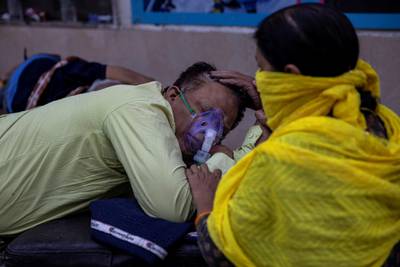 A woman takes care of her husband who is suffering from the coronavirus disease (COVID-19) as he waits to get admitted outside the causality ward at Guru Teg Bahadur hospital, amidst the spread of the disease in New Delhi, India, April 23, 2021. REUTERS/Danish Siddiqui