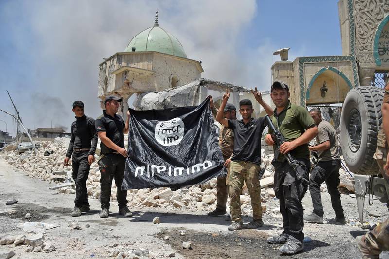 Iraqi Counter-Terrorism Service making the victory gesture as members hold the black ISIS flag upside down outside the destroyed Al Nuri Mosque in the Old City of Mosul after the area was retaken. AFP