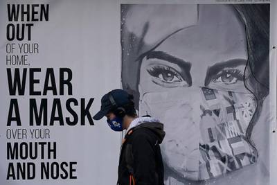 A pedestrian walks past a sign advising mask-wearing in San Francisco, California. AP Photo