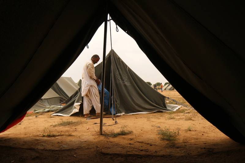 A man sets up camps for people displaced from flooded areas, on the outskirts of Karachi in Pakistan, on September 24, 2022. According to disaster management authorities, flash floods triggered by heavy monsoon rains have killed more than 1,200 people across Pakistan since June 2022. EPA