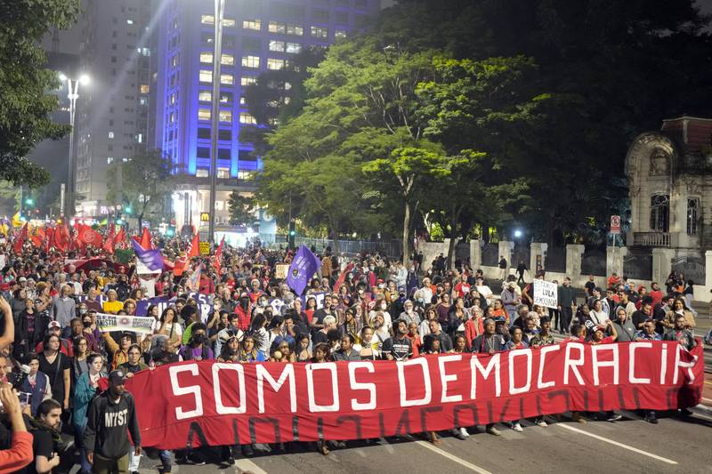 Demonstrators march holding a banner that reads in Portuguese: 'We are democracy.' AP