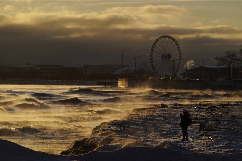 A person takes a picture of the waves crashing onto the shore as ice forms on Oak Street Beach in downtown Chicago. AP 