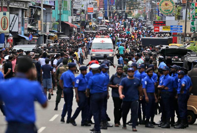 Sri Lankan police officers clear the road for an ambulance.  AP