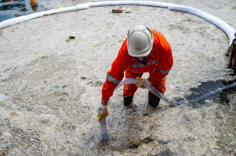 A worker clearing slime that developed on the surface of the water. AFP