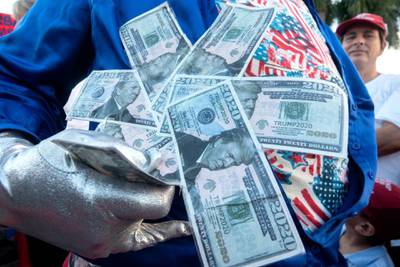 A supporter of US President Donald J. Trump holds fake bills with bearing Trump's face while waiting to attend a 'Make America Great Again Rally' at the Opa-Locka International Airport in Opa-Locka, Florida, US.  EPA