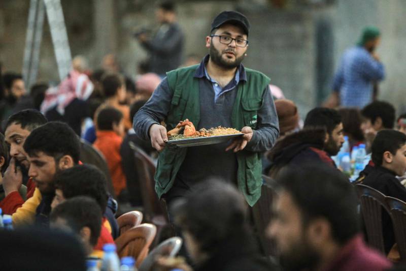 A volunteer serves a meal to displaced Syrians during a community iftar, donated by the independent civil society organisation Ulfah, with support from Malaysia, near the city of Al Bab. AFP