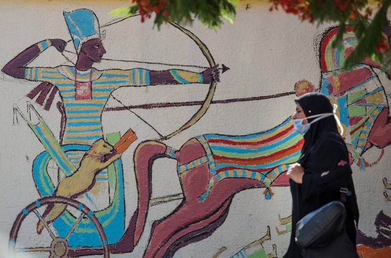 A woman wearing a face mask passing by a mural depicting a pharaonic graffiti in Cairo, Egypt.  EPA