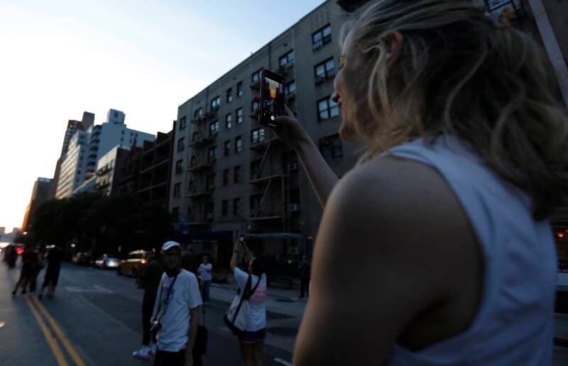 A woman takes a picture on her mobile phone on 57th Street during Manhattanhenge. EPA