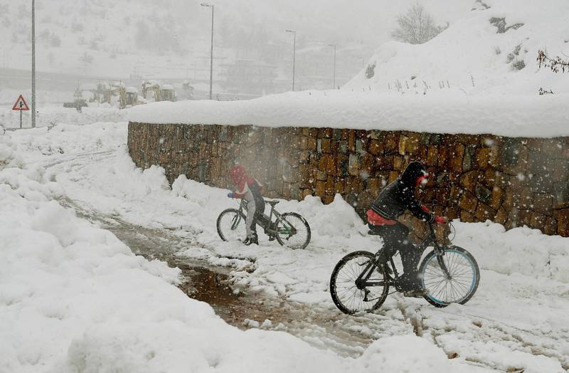Youths ride their bicycles along a snow-covered road in the town of Hasroun in Mount Lebanon. AFP