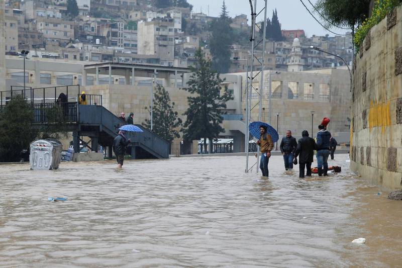People cross a flooded street in Amman. Reuters