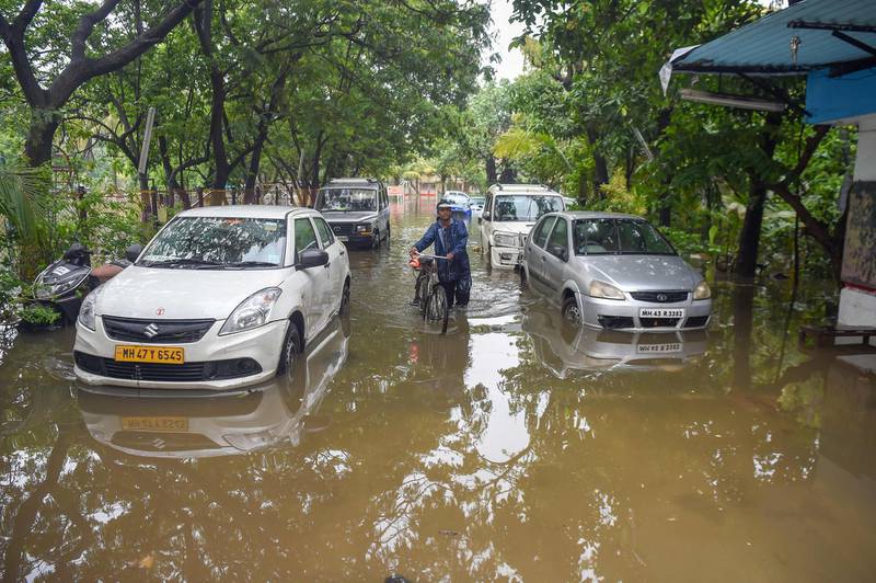 An Indian man walks with a bicycle along a waterlogged street in Mumbai on July 2, 2019. AFP