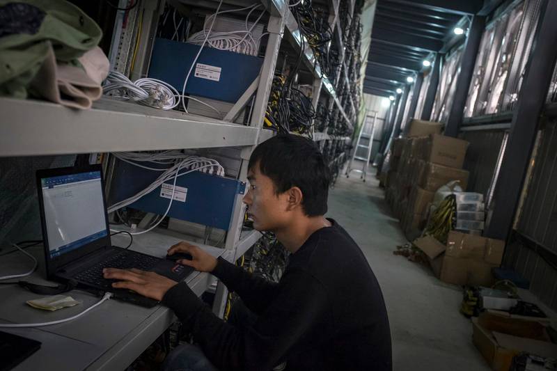 In this Sept. 28, 2016, photo, a man sets up a new bitcoin mining machine to connect to the internet at a bitcoin mine built beside a hydropower station in a remote valley in Aba prefecture in southwestern China's Sichuan province. The launch of a U.S. futures contract for bitcoin on Sunday, Dec 10, 2017, underscores the virtual currency's increasing mainstream acceptance, including in many parts of Asia, where it already has a wide following among speculators and investors. (Chinatopix via AP)