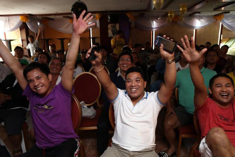 Martin Siron, left, Dodong Cababan, and Jojo Lumilan cheer for Manny Pacquiao during his fight with Brandon Rios fight at the Philippine House Restaurant in Abu Dhabi. Sammy Dallal / The National 