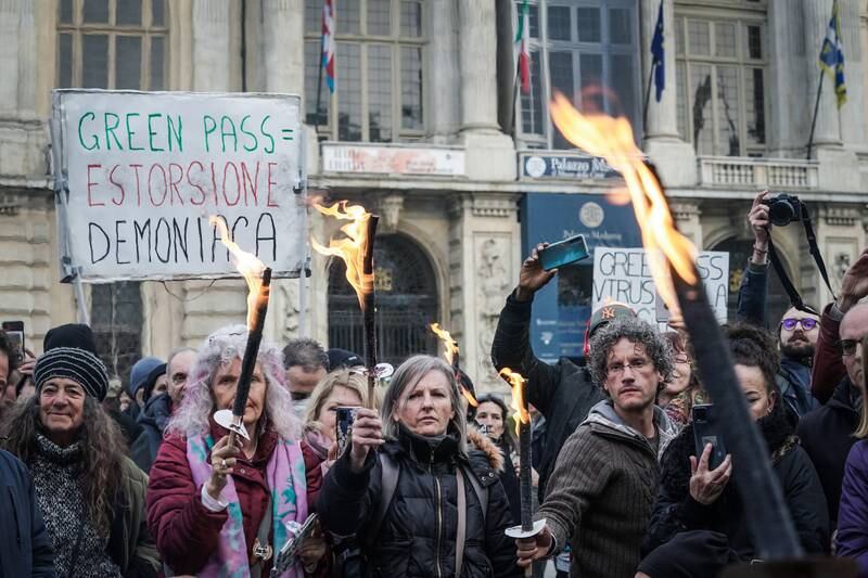 Protesters hold torches to burn Covid-19 vaccination passes, during a demonstration at Castello Square, in Turin, Italy. EPA