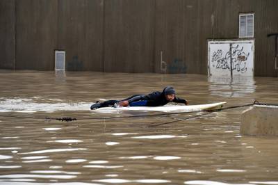 A man uses a paddleboard on a flooded after a heavy downpour on the main road near Rafic Hariri International Airport at the southern entrance of Beirut.  EPA