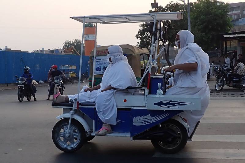 Jain monks ride an electric vehicle along a street in Ahmedabad.