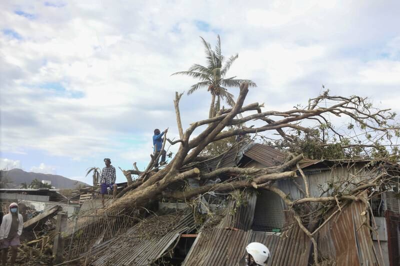 Villagers work on removing a toppled tree from the top of a house in Bohol, the Philippines. EPA