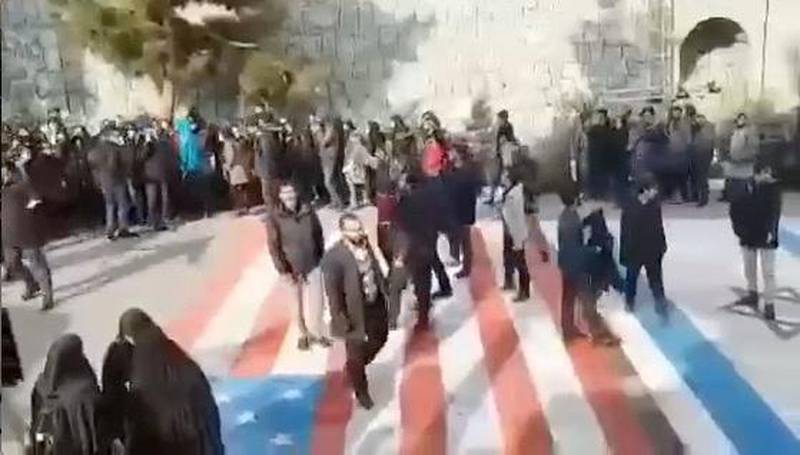 Several people walk on US and Israeli flags while others avoid stepping on the flags by walking around them, at the Shahid Beheshti University in Tehran, Iran.  Reuters