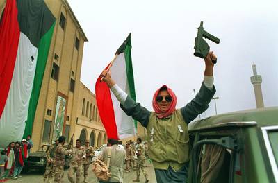 (FILES) In this file photo taken on February 28, 1991, A member of the Kuwaiti resistance raises his rifle and the national flag in celebration as Kuwaiti's filled the streets after US President George Bush's announcement of a cease-fire. Thirty years have passed since Iraqi tyrant Saddam Hussein invaded neighbouring Kuwait, but despite hints of a diplomatic rapprochement, people both countries say the wounds have yet to heal. On August 2, 1990, Saddam sent his military, already exhausted by an eight-year conflict with Iran, into Kuwait to seize what he dubbed "Iraq's 19th province." The two-day operation turned into a seven-month occupation and, for many Iraqis, opened the door to 30 years of devastation which is still ongoing. / AFP / Bob PEARSON
