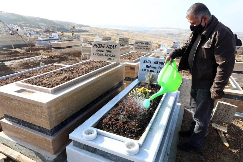 A man waters flowers on a grave in Ortakoy cemetery, the main burial site for people who died during the Covid-19 novel coronarivus pandemic in Mamak, district of Ankara, on December 10, 2020. / AFP / Adem ALTAN
