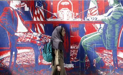 An Iranian woman walks past an anti-US mural near the former American embassy in Tehran. EPA