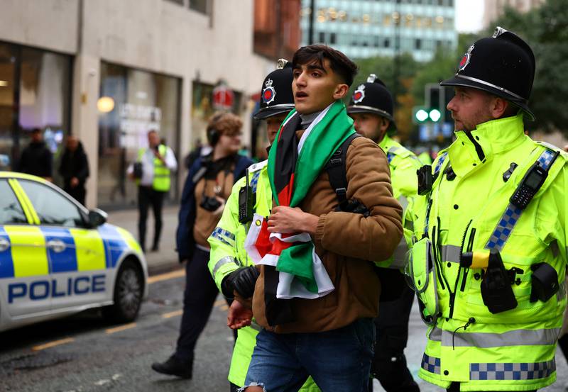 Police detain a man with a Palestine flag at a vigil for Israel held by Manchester Jewish Community in Manchester, on Wednesday. Reuters