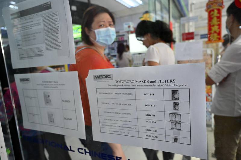 People queue to purchase protective face mask, sanitizer and thermometer at a pharmacy in Singapore. AFP