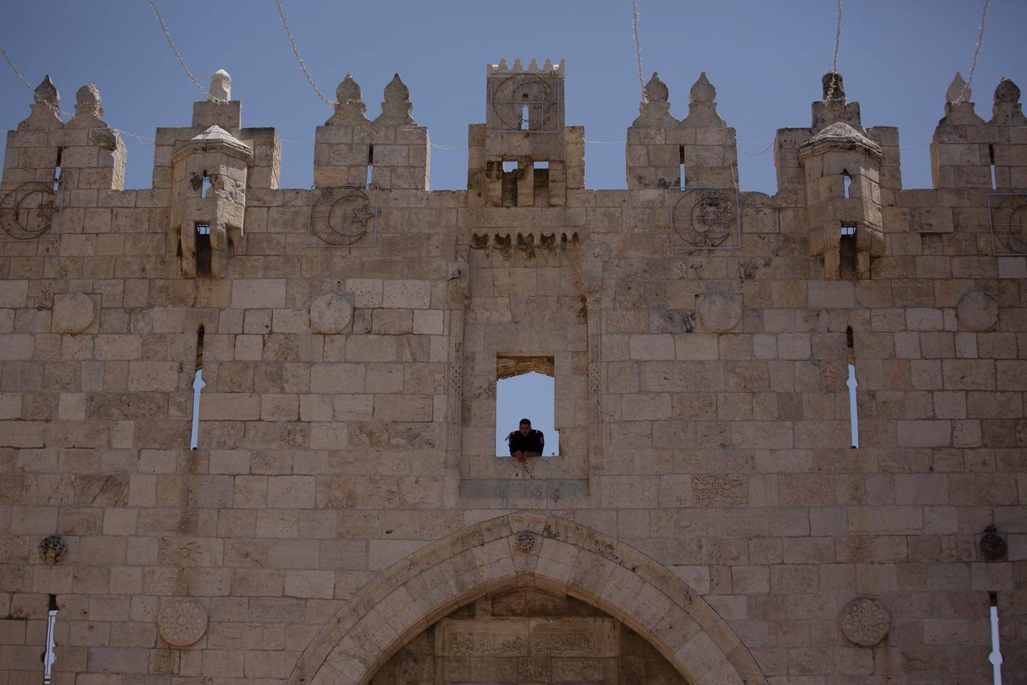 Israeli policeman uses the Damascus Gate to watch Muslim worshippers leave the Old City of Jerusalem after Friday prayers during the Muslim holy month of Ramadan, on Friday, April 23, 2021 in Jerusalem.  Israeli police say 44 people were arrested and 20 officers were wounded in a night of chaos in Jerusalem, where security forces separately clashed with Palestinians angry about Ramadan restrictions and Jewish extremists who held an anti-Arab march nearby. (AP Photo/Maya Alleruzzo)