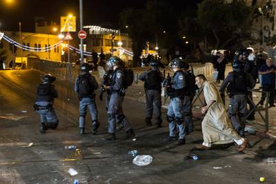 A Palestinian man flees as Israeli police officers watch during clashes in Jerusalem's Old City. Getty Images