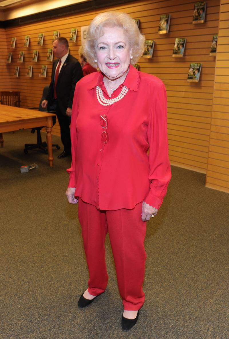 Betty White, in a red set with pearls, signs copies of her new book 'Betty & Friends: My Life at the Zoo' in Santa Monica on December 19, 2011. AFP