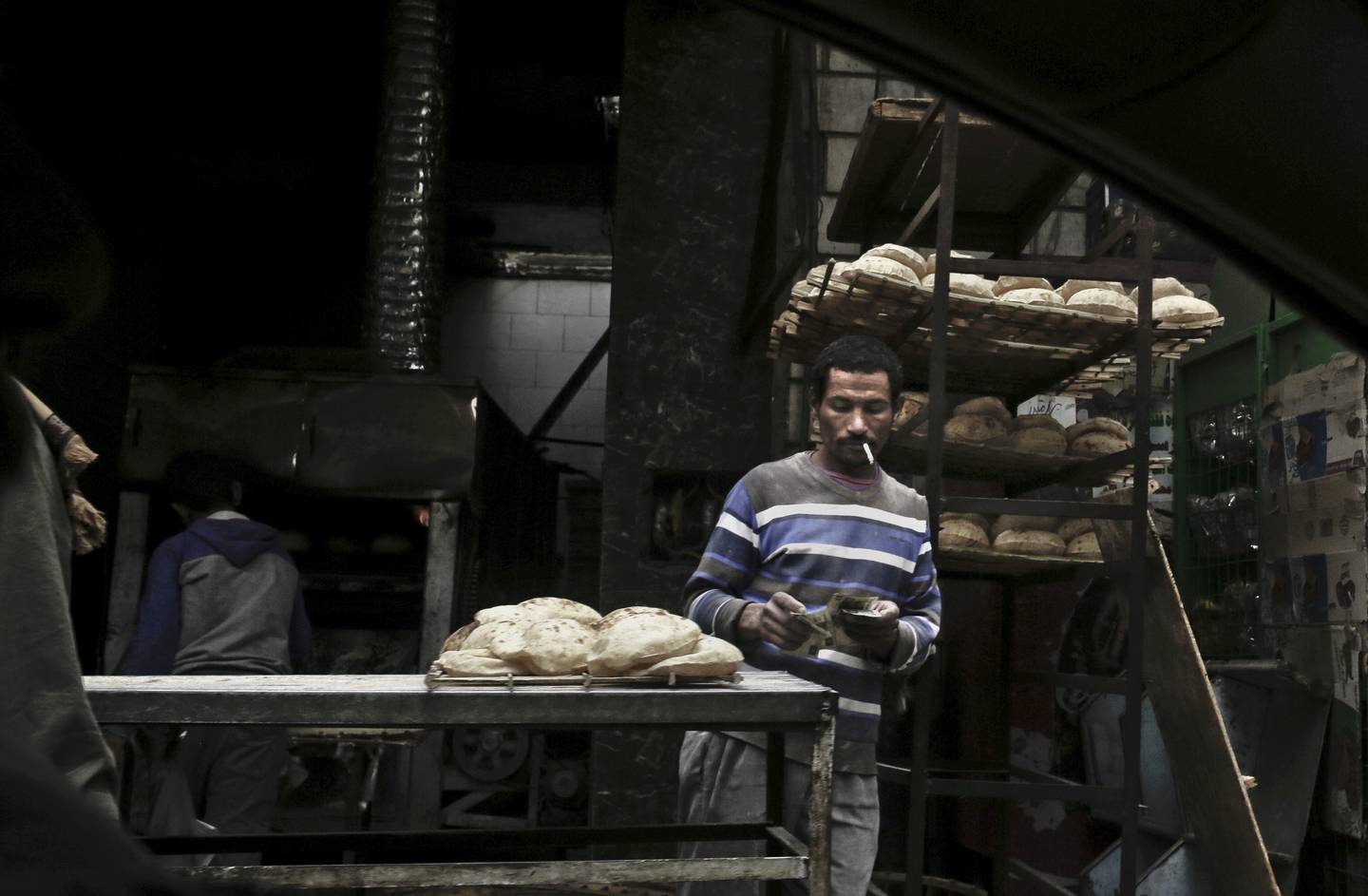 A vendor counts his money at a bread stand in the Sayeda Zeinab neighbourhood of Cairo, Egypt. AP