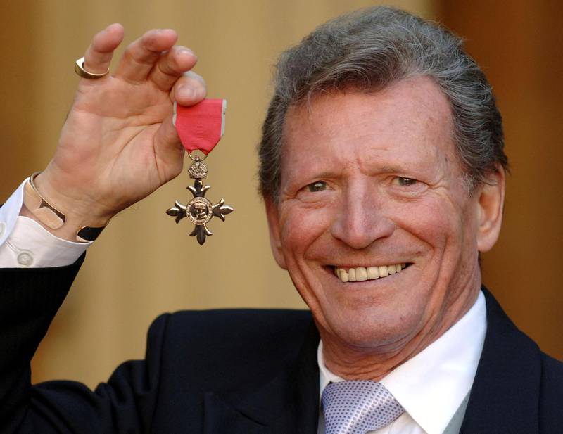 FILE - In this March 7, 2007 file photo, actor Johnny Briggs poses for the media after collecting an MBE from Queen Elizabeth II at Buckingham Palace in London. British actor Johnny Briggs, best known for his role as businessman Mike Baldwin in the long-running TV soap opera â€œCoronation Street,â€ has died. He was 85. A statement from his family released Sunday, Feb. 28, 2021 said Briggs died peacefully after a long illness. (Fiona Hanson/PA via AP, file)