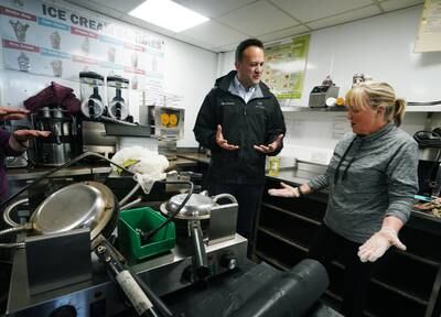 Irish Taoiseach Leo Varadkar speaks with a woman cleaning up flood damage at a business in Midleton, Co Cork, in the Republic of Ireland. PA