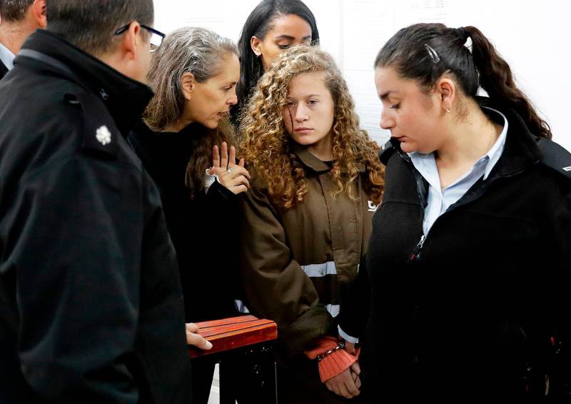 Israeli lawyer Gaby Lasky (C-L) speaks with her client sixteen-years-old Ahed Tamimi (2R) before she stands for a hearing in the military court at Ofer military prison in the West Bank village of Betunia on January 1, 2018. 
Israeli authorities are seeking 12 charges against Ahed  after a video of her slapping and kicking two Israeli soldiers in the West Bank went viral, her lawyer said. / AFP PHOTO / Ahmad GHARABLI