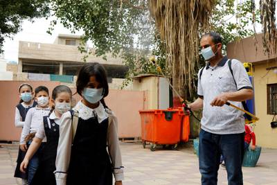 A worker wearing a protective face mask disinfects Iraqi students as they arrive to take their mid-year exams, amid the spread of the coronavirus disease at a school in Baghdad, Iraq. Reuters