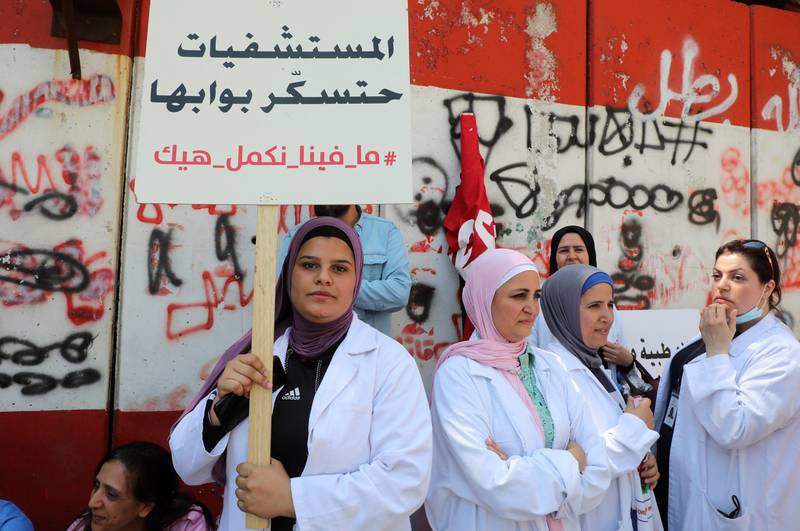 A healthcare worker holds a placard reading "Hospitals will close their doors, we cannot continue this way" during a protest against banks restricting cash dealings for hospitals, in front of Lebanon's Central Bank building in Beirut on May 26, 2022. Reuters