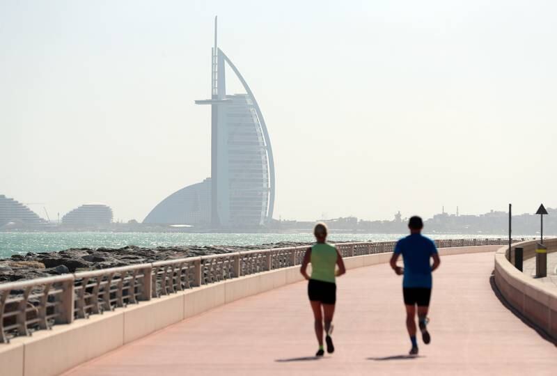 People enjoy a run on the Palm Jumeirah on a hazy but bright day in Dubai. Photo: Chris Whiteoak / The National
