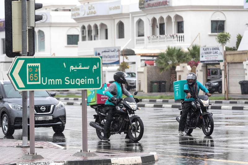 DUBAI, UNITED ARAB EMIRATES. 15 APRIL 2020. Rain pours down in Dubai. Deliveroo motorcycle drivers wait at a traffic light on Al Wasl rd in the rain. (Photo: Antonie Robertson/The National) Journalist: STANDALONE. Section: National.