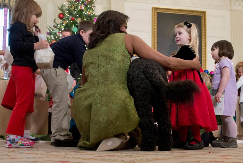 In this December 2015 photo, Michelle Obama, with dog Bo, is surrounded by children in the State Dining Room of the White House. AP