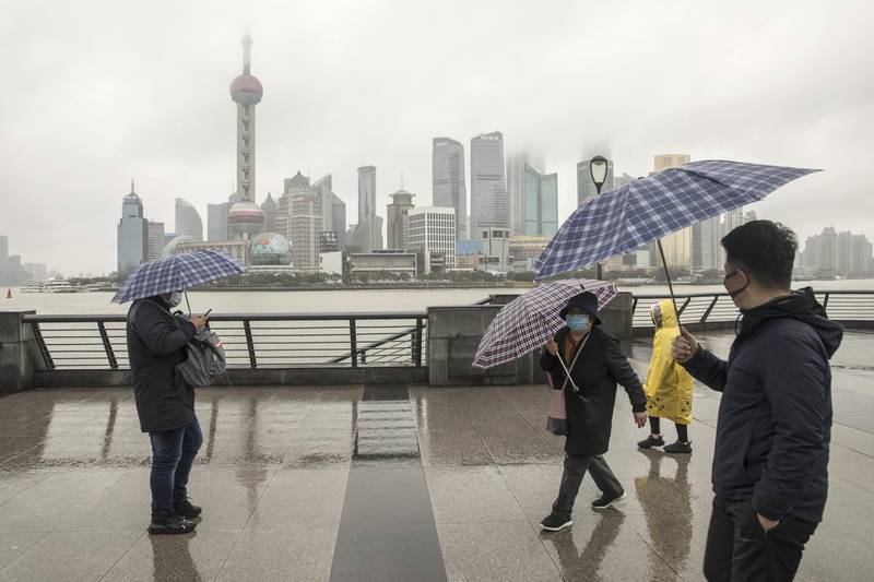 Pedestrians wearing protective masks and holding umbrellas walk in the Bund area as skyscrapers of the Pudong Lujiazui Financial District stand across the Huangpu River in Shanghai, China, on Saturday, Jan. 25, 2020. The novel coronavirus, which has killed at least 41 people in China, has spread to more countries in the Asia Pacific, with Australia and Malaysia confirming infections. Photographer: Qilai Shen/Bloomberg