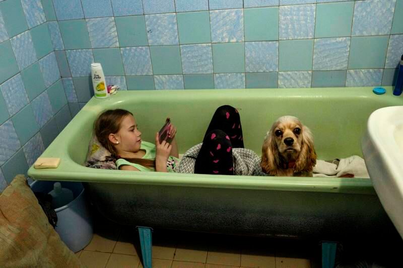 Zlata-Maria Shlapak, 8, sits in a bathtub with her 9-month-old puppy Letti as an air siren goes off in the Ukrainian city of Lviv, where her family rented a flat after fleeing from Kharkiv, on April 2, 2022, just days after Russian forces invaded Ulraine. Nariman El-Mofty / AP