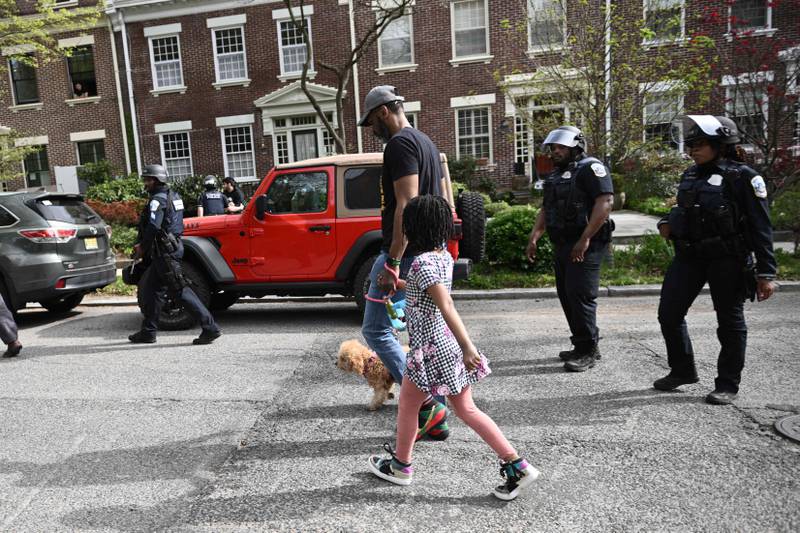 A man walks with a girl and dog past police officers following the shooting. AFP