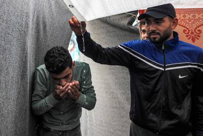 Men use their hands to drink rainwater dripping from the roof of a tent amid water shortages while at a school run by the UN Relief and Works Agency for Palestine Refugees in the Near East (UNRWA) in Rafah in the southern Gaza Strip. AFP