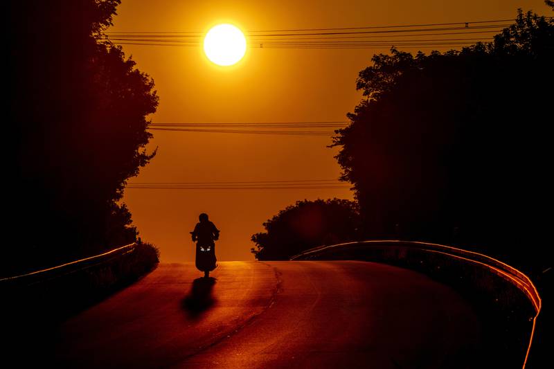 A motorcyclist rides over a hill on the outskirts of Frankfurt, Germany as the sun rises. AP Photo
