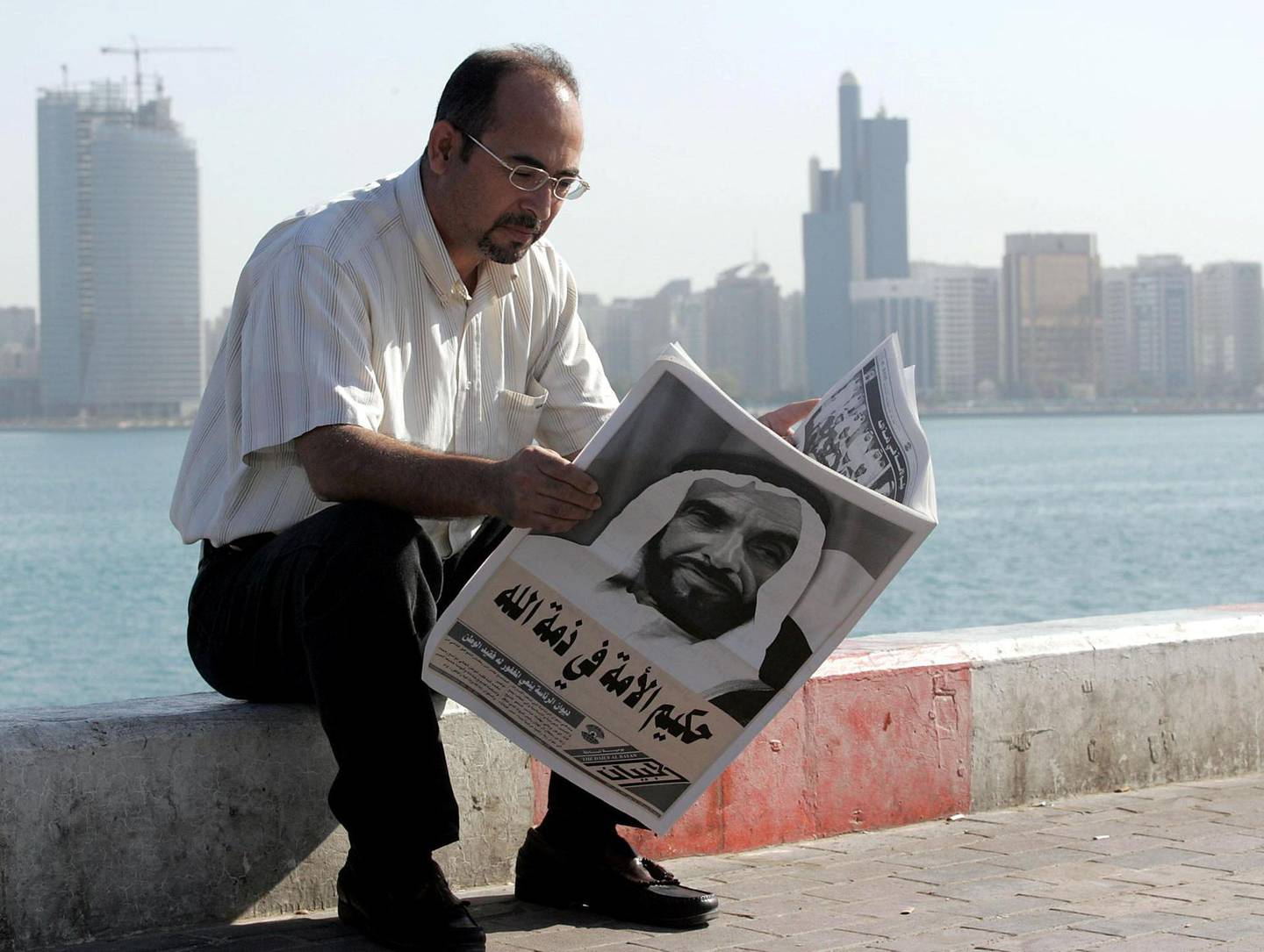 A man reads the newspapers with Sheikh Zayed bin Sultan al-Nahayan's portrait covering the whole front page during the funeral procession of the United Arab Emirate's late president in Abdu Dhabi 03 November 2004. Nahayan, the founding father of the Gulf emirates federation, died 02 November 2004 after more than 30 years at the helm of his oil-rich country.     AFP PHOTO/RABIH MOGHRABI / AFP PHOTO / RABIH MOGHRABI