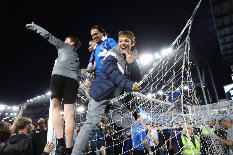 Everton fans climb on the frame of the goal. Action Images