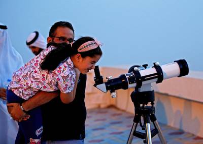 A man helps his daughter to look through a telescope trying to sight the new crescent moon.  EPA