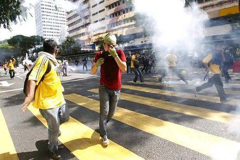 Malaysian protesters take cover from tear gas fired by police during clashes in Kuala Lumpur.